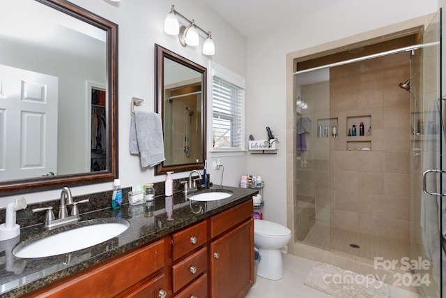 bathroom featuring tile patterned flooring, vanity, toilet, and a shower with door