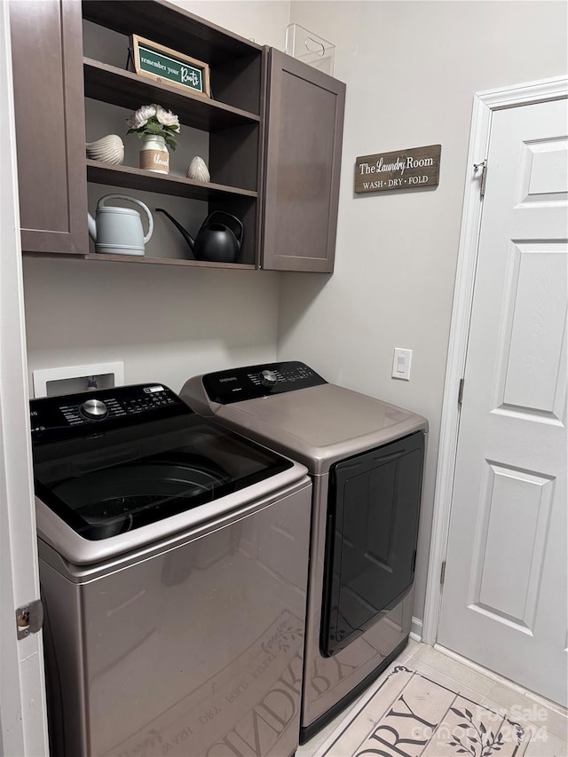 washroom featuring cabinets, light tile patterned floors, and washer and clothes dryer