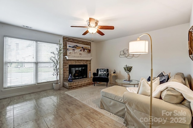 living room with a brick fireplace, ceiling fan, and light tile patterned flooring