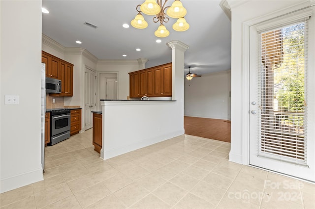 kitchen featuring hanging light fixtures, ornamental molding, stainless steel appliances, and a wealth of natural light