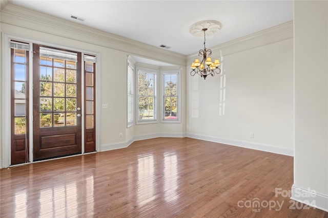 unfurnished dining area featuring a chandelier, hardwood / wood-style flooring, a wealth of natural light, and crown molding