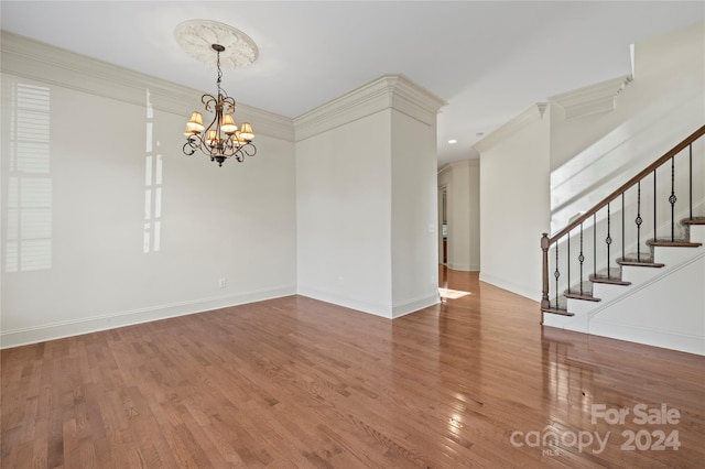 unfurnished room with wood-type flooring, ornamental molding, and an inviting chandelier