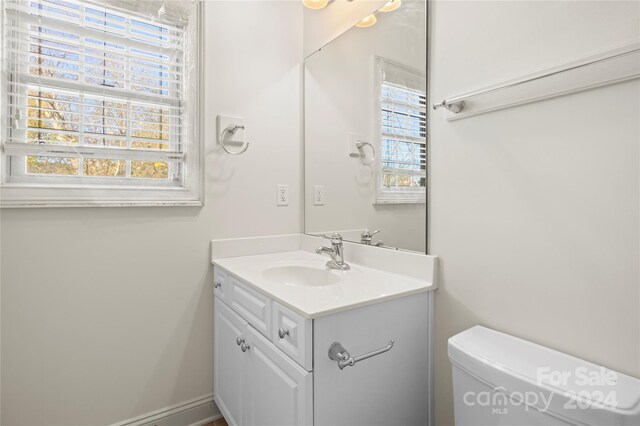 bathroom featuring vanity, toilet, and a healthy amount of sunlight