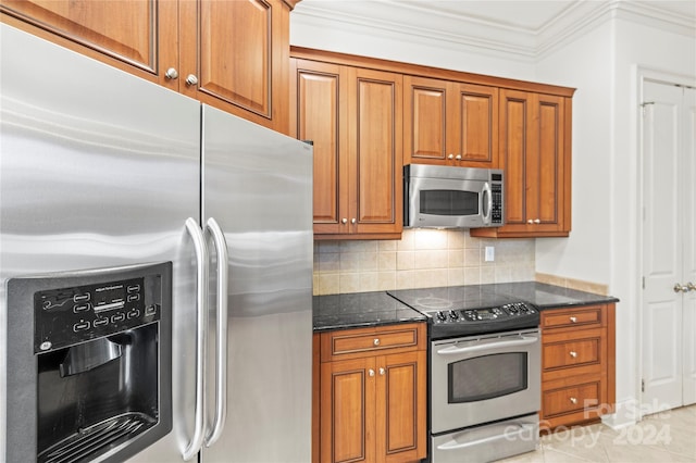 kitchen with appliances with stainless steel finishes, tasteful backsplash, crown molding, light tile patterned floors, and dark stone countertops