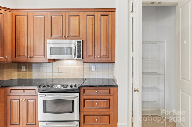 kitchen featuring decorative backsplash, stainless steel appliances, and dark stone counters