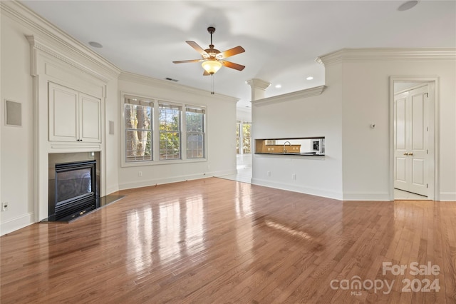 unfurnished living room with light hardwood / wood-style floors, ceiling fan, and ornamental molding