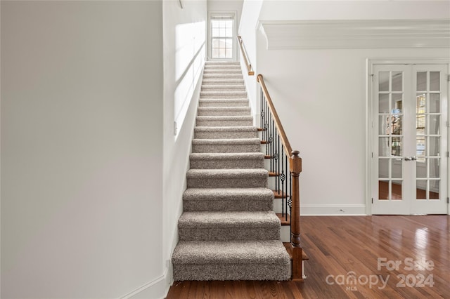 staircase with hardwood / wood-style floors and french doors