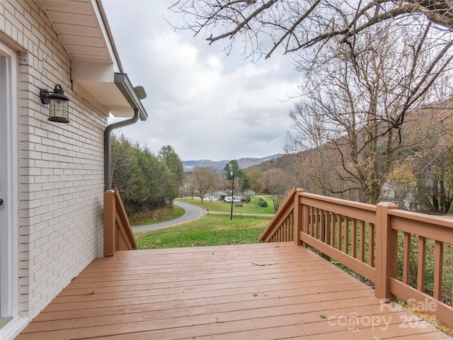 wooden terrace featuring a mountain view and a lawn