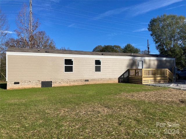 back of property with a yard and a wooden deck