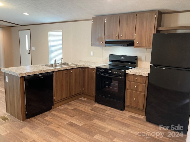 kitchen with kitchen peninsula, sink, black appliances, light hardwood / wood-style flooring, and range hood