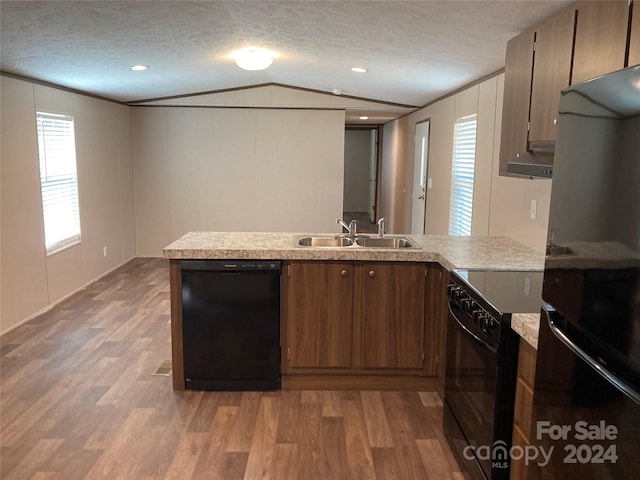 kitchen featuring a textured ceiling, sink, black appliances, and vaulted ceiling