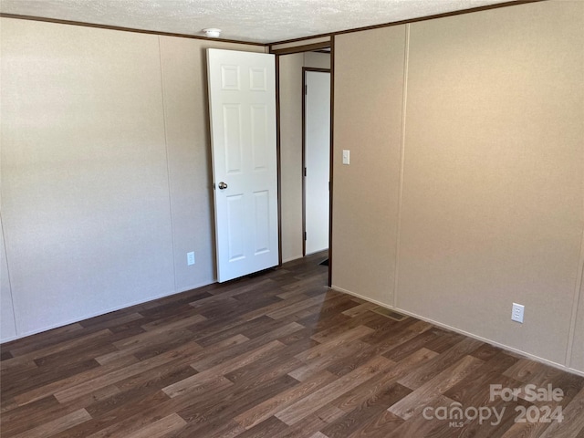 empty room with a textured ceiling and dark hardwood / wood-style floors