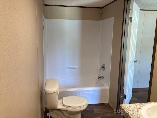 full bathroom with hardwood / wood-style flooring, toilet, shower / tub combination, and a textured ceiling