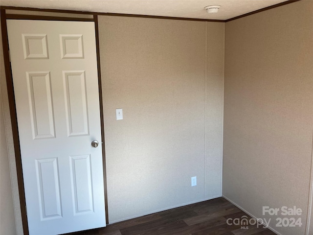 empty room featuring dark hardwood / wood-style flooring and ornamental molding