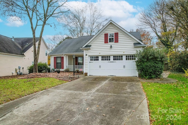 view of front of house with covered porch, a front yard, and a garage