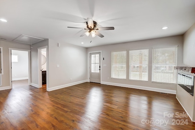 unfurnished living room with dark hardwood / wood-style flooring and ceiling fan