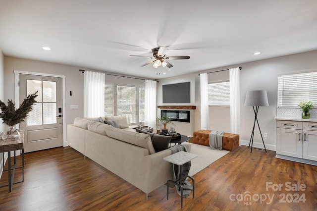 living room with plenty of natural light, ceiling fan, and dark wood-type flooring