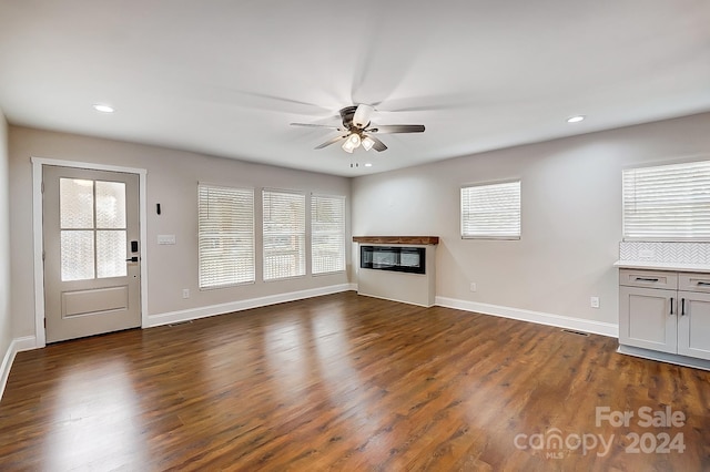 unfurnished living room featuring ceiling fan, dark wood-type flooring, and a healthy amount of sunlight