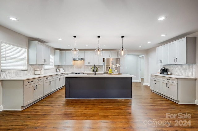 kitchen with white cabinets, stainless steel fridge, dark hardwood / wood-style flooring, and an island with sink