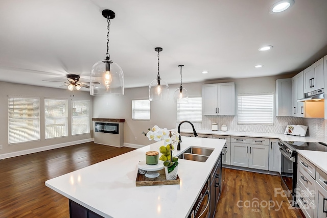 kitchen with a wealth of natural light, stainless steel electric range oven, sink, and a kitchen island with sink