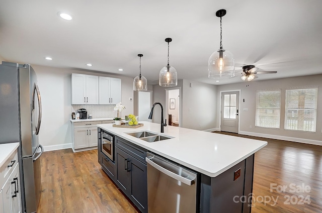 kitchen with white cabinets, sink, appliances with stainless steel finishes, and an island with sink