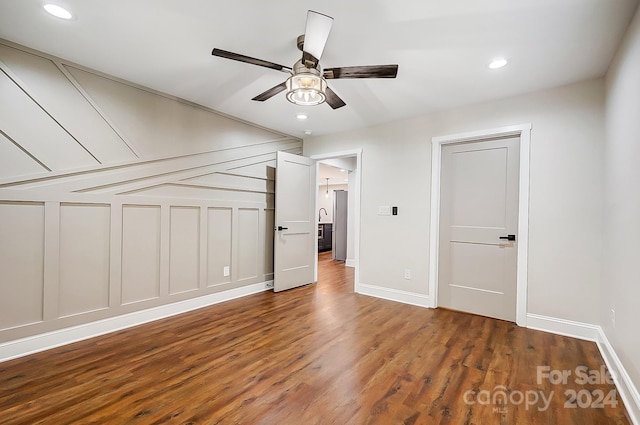 unfurnished bedroom with stainless steel fridge, dark hardwood / wood-style flooring, and ceiling fan