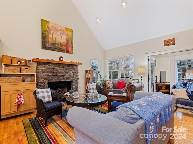 living room featuring a fireplace, plenty of natural light, high vaulted ceiling, and light hardwood / wood-style floors