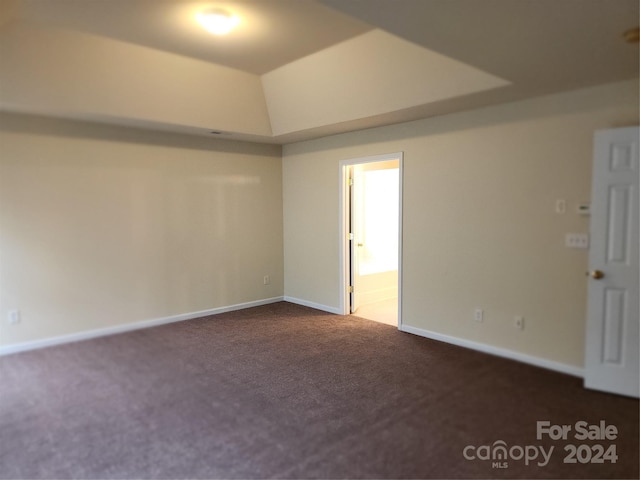 empty room featuring dark carpet and lofted ceiling