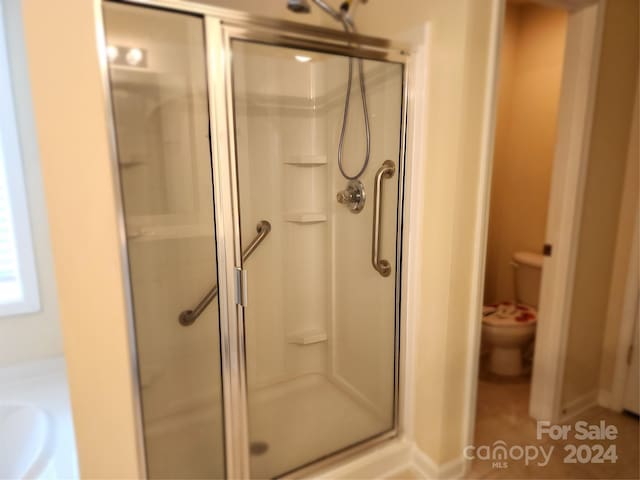 bathroom featuring toilet and a shower with shower door