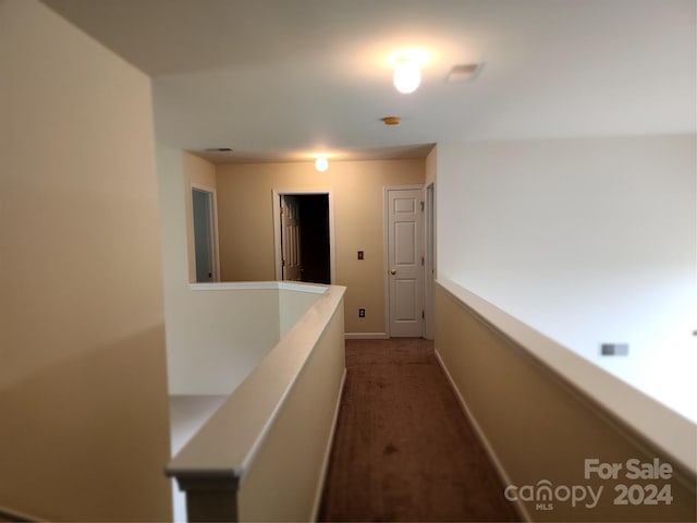 corridor featuring dark colored carpet