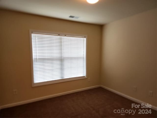 unfurnished room featuring dark colored carpet