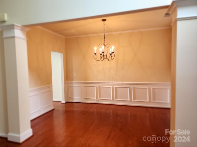 empty room with ornamental molding, dark wood-type flooring, and an inviting chandelier