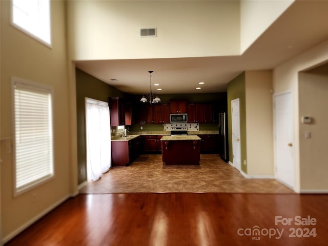 kitchen featuring a center island, an inviting chandelier, hardwood / wood-style floors, decorative light fixtures, and appliances with stainless steel finishes