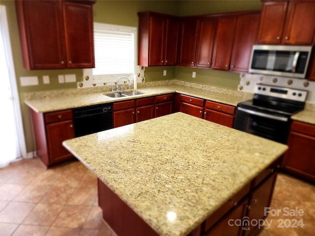 kitchen with sink, light stone counters, a kitchen island, and black appliances