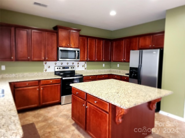 kitchen featuring light stone counters, a center island, and stainless steel appliances