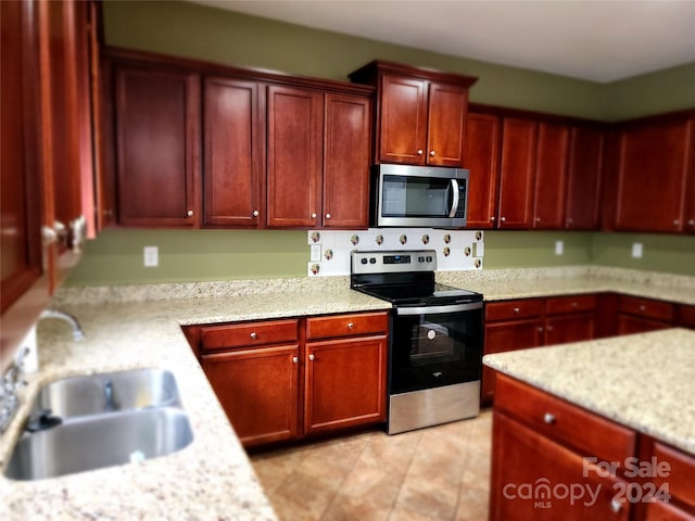 kitchen with light stone countertops, sink, and appliances with stainless steel finishes