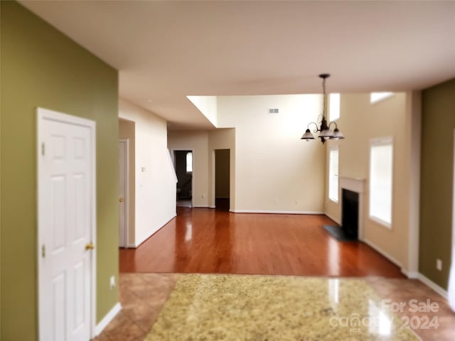 unfurnished living room with wood-type flooring and an inviting chandelier