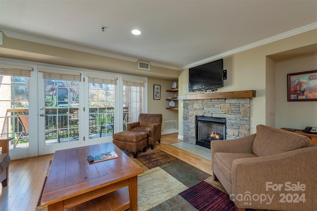 living room with a fireplace, light wood-type flooring, a wealth of natural light, and ornamental molding