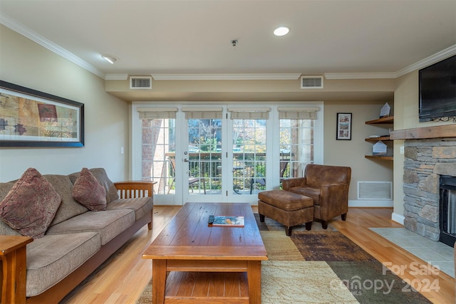 living room with a stone fireplace, light hardwood / wood-style flooring, and ornamental molding