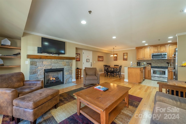 living room featuring sink, a stone fireplace, light wood-type flooring, and ornamental molding