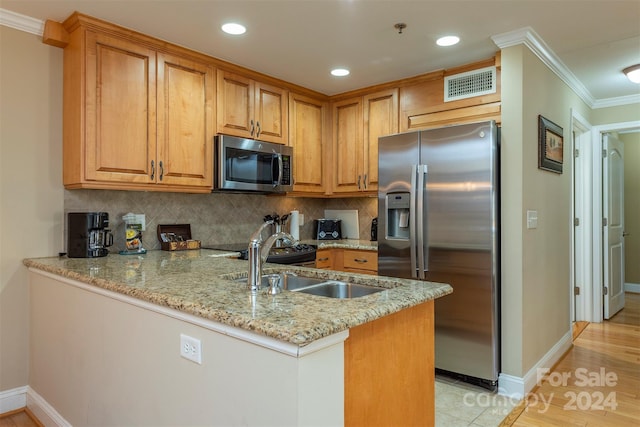 kitchen with kitchen peninsula, light stone counters, light wood-type flooring, and appliances with stainless steel finishes