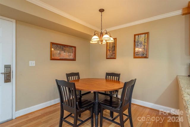 dining area featuring light wood-type flooring, ornamental molding, and a notable chandelier