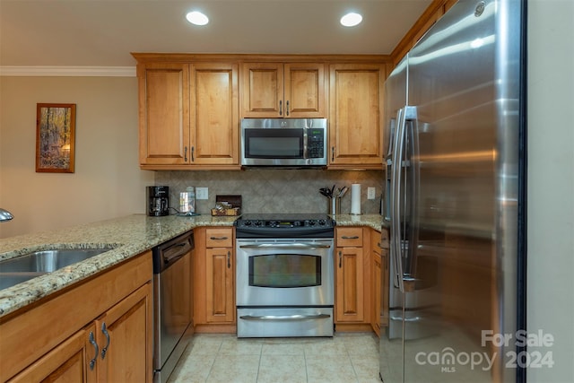 kitchen with light stone countertops, appliances with stainless steel finishes, kitchen peninsula, ornamental molding, and light tile patterned floors