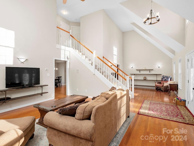 living room featuring a chandelier, light hardwood / wood-style flooring, and high vaulted ceiling