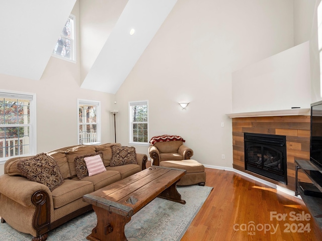 living room with a tile fireplace, light hardwood / wood-style floors, and high vaulted ceiling