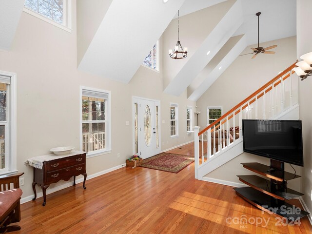 entrance foyer featuring wood-type flooring, ceiling fan with notable chandelier, and high vaulted ceiling