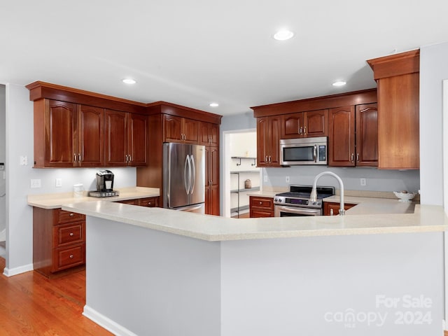 kitchen with kitchen peninsula, stainless steel appliances, and light hardwood / wood-style floors