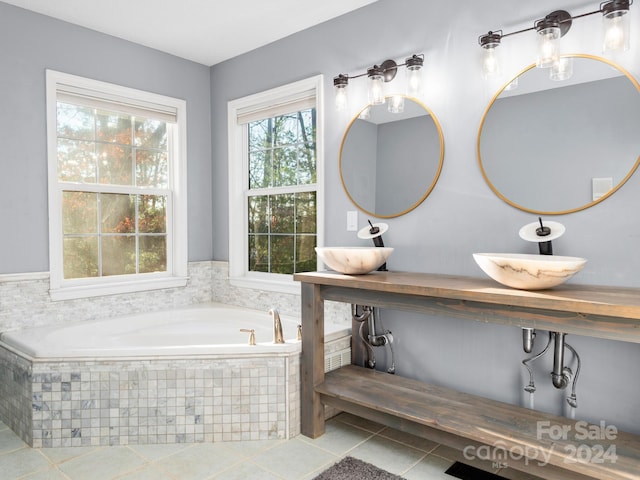 bathroom with tile patterned floors, sink, and tiled bath