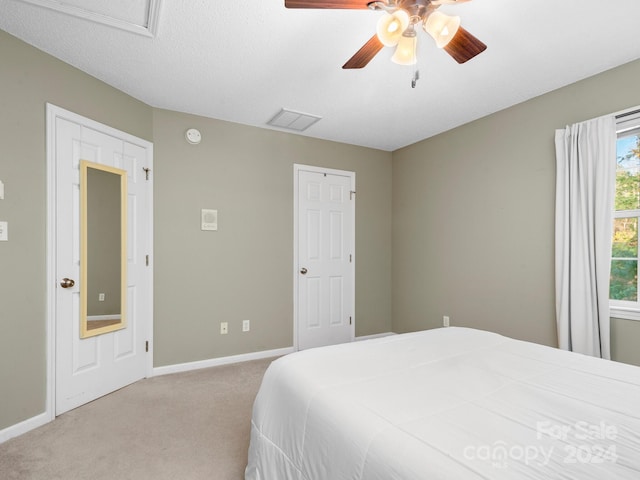 carpeted bedroom with ceiling fan and a textured ceiling