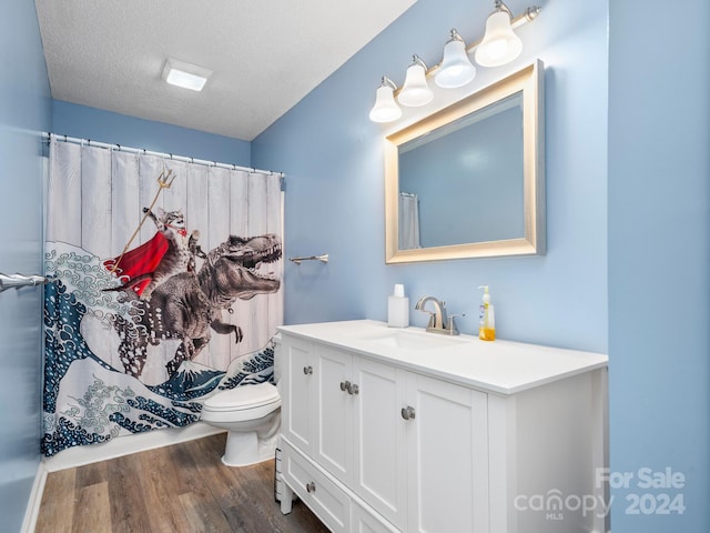 bathroom featuring a shower with shower curtain, vanity, a textured ceiling, hardwood / wood-style flooring, and toilet